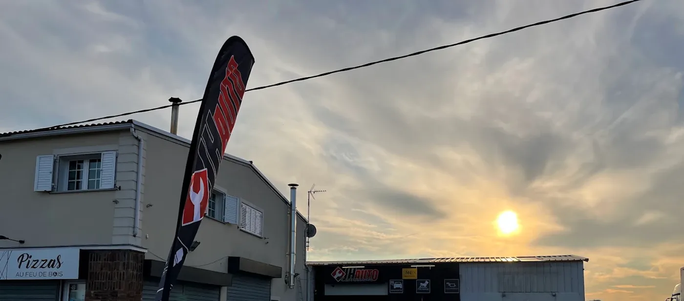 L'enseigne et le drapeau JH Auto au crépuscule, route de Paris