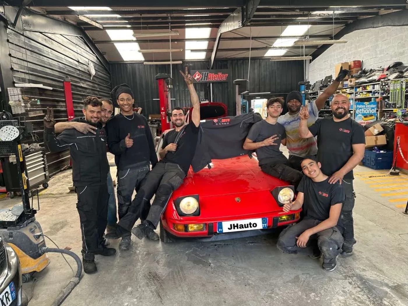 L'équipe de JH Auto réunie dans l'atelier autour d'une Porsche 924 rouge